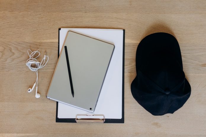 clipboard tablet headphones and black hat on a table