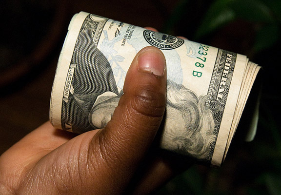 Hand holding role of dollar bills